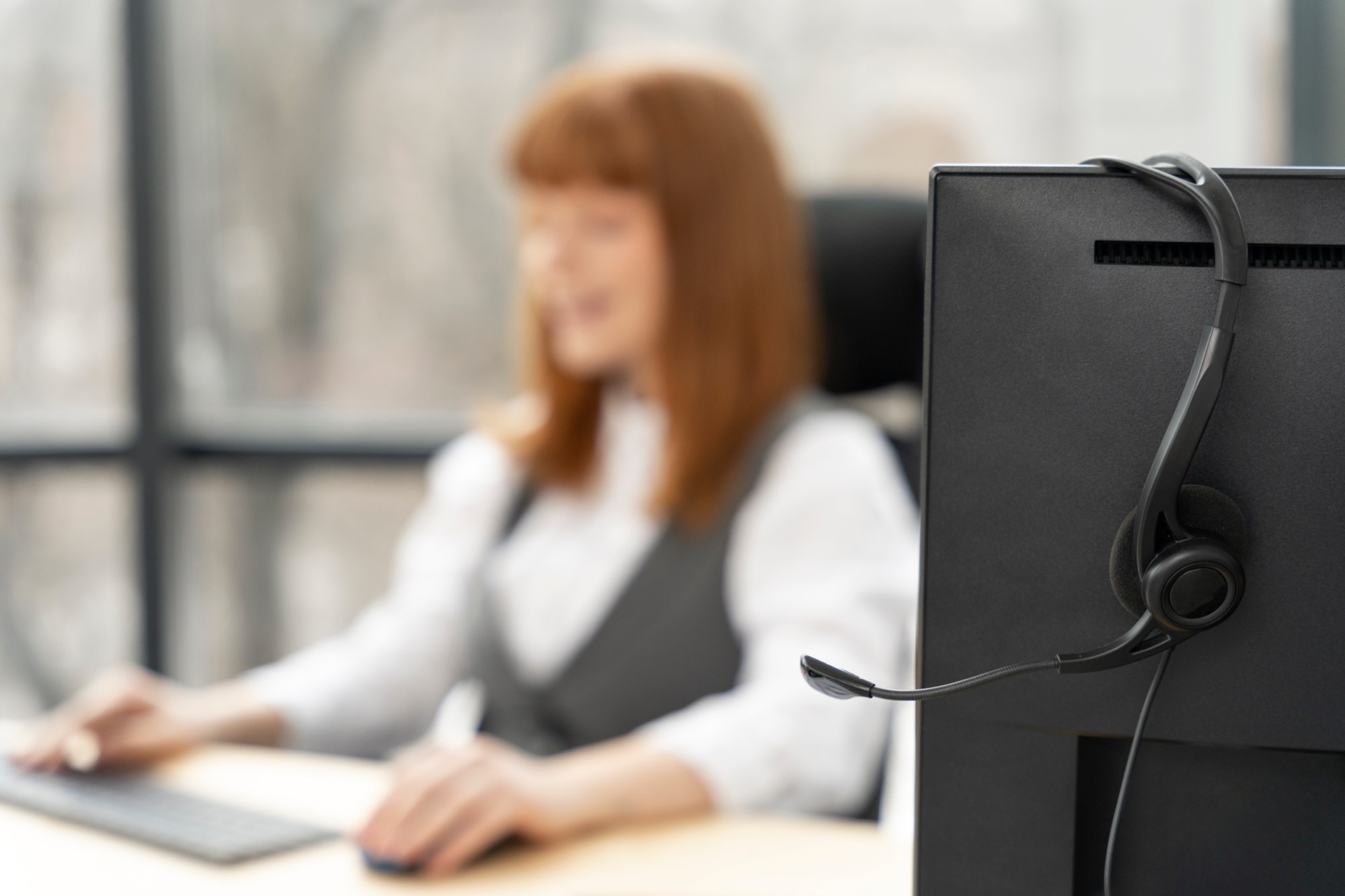 Operatrice con cuffie a una postazione di lavoro